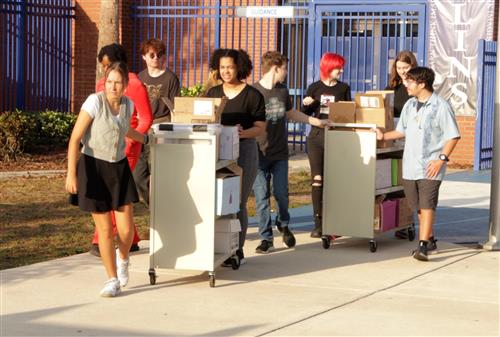 Students wheeling carts of books